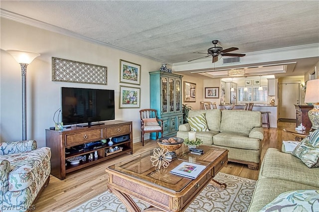 living room with crown molding, light hardwood / wood-style floors, a textured ceiling, and ceiling fan