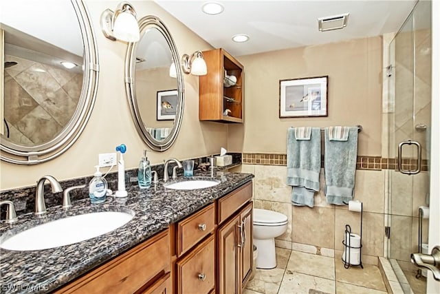 bathroom featuring toilet, oversized vanity, double sink, tile walls, and tile flooring