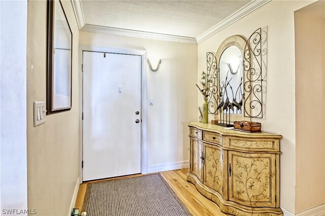 entryway with ornamental molding and light hardwood / wood-style floors