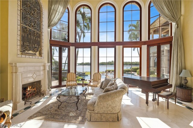 living room featuring a water view, a fireplace, and a high ceiling