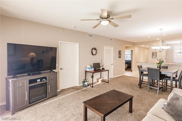 living room featuring light carpet and ceiling fan with notable chandelier