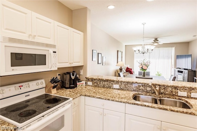 kitchen with sink, light stone counters, white cabinets, range, and ceiling fan with notable chandelier