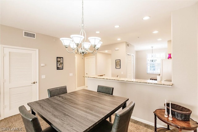 dining room featuring light carpet and a chandelier