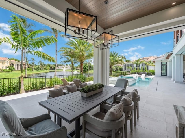 view of patio / terrace with a fenced in pool, outdoor dining space, a water view, and fence