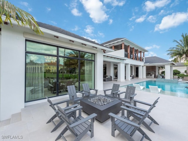 exterior space with an outdoor fire pit, a balcony, and an outdoor pool