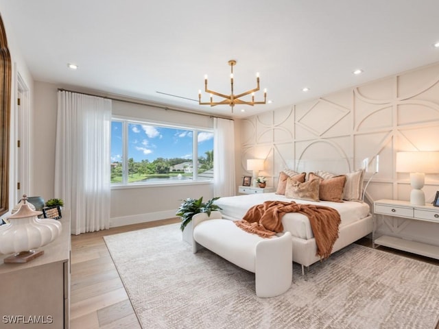 bedroom featuring an accent wall, light wood-type flooring, a chandelier, a decorative wall, and recessed lighting