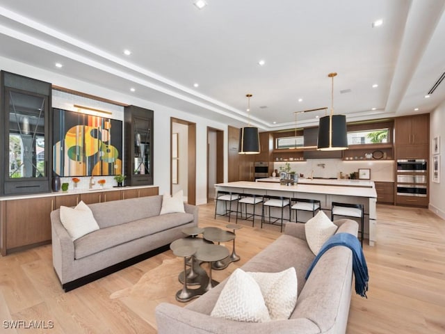 living area featuring light wood-style floors, a tray ceiling, and recessed lighting