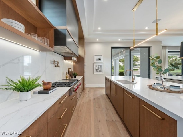 kitchen with modern cabinets, a sink, light wood-type flooring, stainless steel gas cooktop, and backsplash