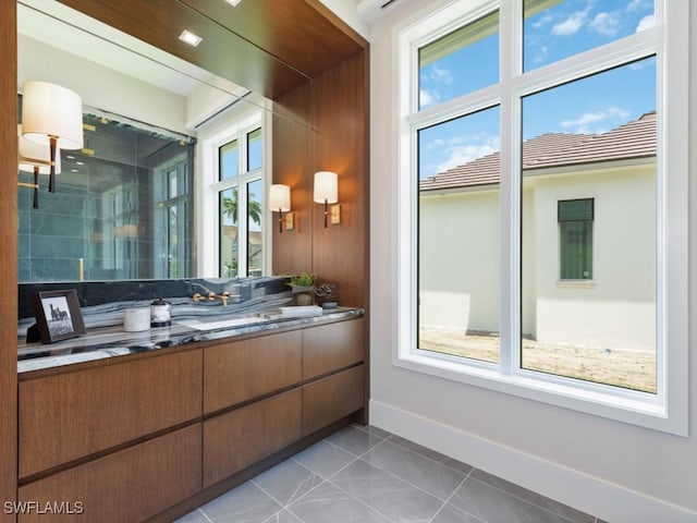 full bath with a healthy amount of sunlight, a shower with door, vanity, and tile patterned floors
