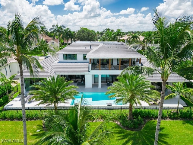 rear view of property featuring a fenced in pool, a patio, a lawn, a balcony, and a fenced backyard
