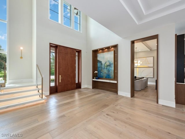 entrance foyer featuring light wood-type flooring, a healthy amount of sunlight, and an inviting chandelier