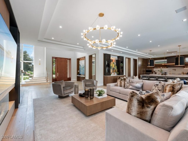 living area featuring an inviting chandelier, light wood-style flooring, a tray ceiling, and recessed lighting