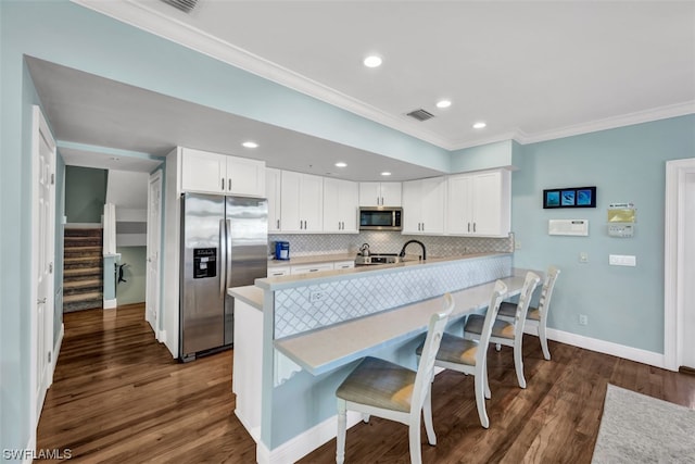 kitchen with tasteful backsplash, white cabinetry, dark hardwood / wood-style flooring, and appliances with stainless steel finishes