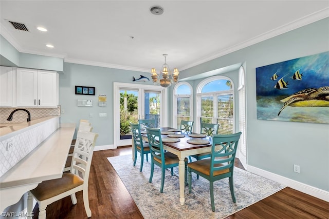 dining area with a chandelier, dark wood-type flooring, french doors, and crown molding