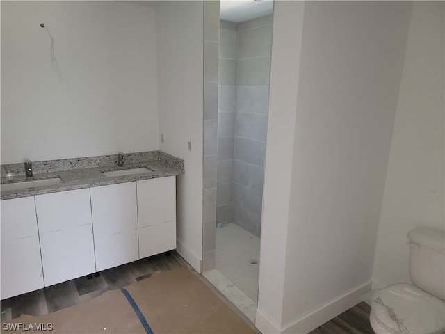 bathroom featuring vanity, wood-type flooring, toilet, and tiled shower