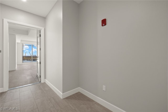 hallway with tile patterned flooring and baseboards