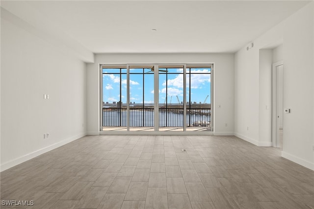 empty room featuring a water view and baseboards