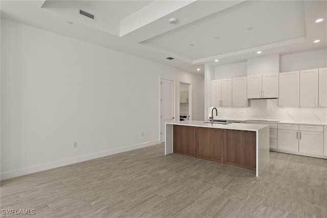 kitchen featuring tasteful backsplash, a tray ceiling, visible vents, and a sink