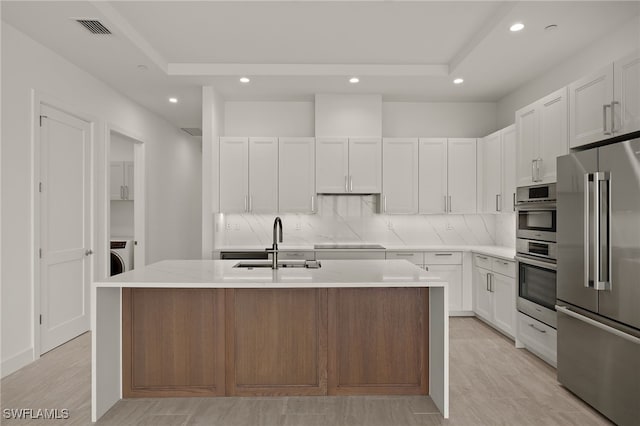 kitchen featuring a sink, visible vents, appliances with stainless steel finishes, washer / clothes dryer, and tasteful backsplash