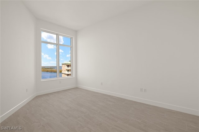 spare room featuring a water view and baseboards