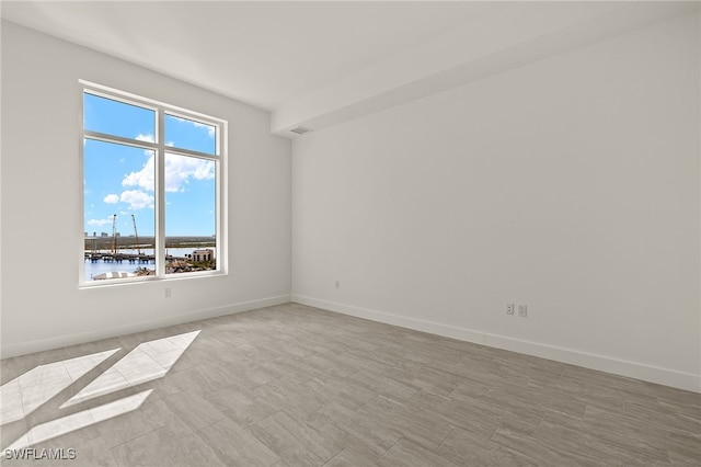 spare room with a water view and baseboards