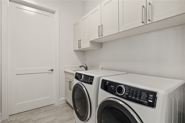 clothes washing area featuring cabinet space, a sink, and washing machine and clothes dryer