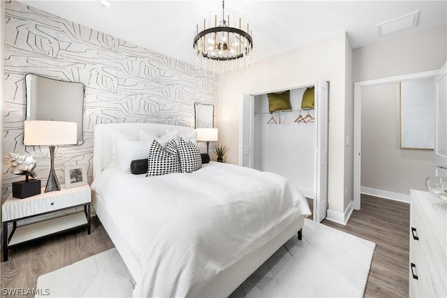 bedroom with a closet, wood-type flooring, and an inviting chandelier