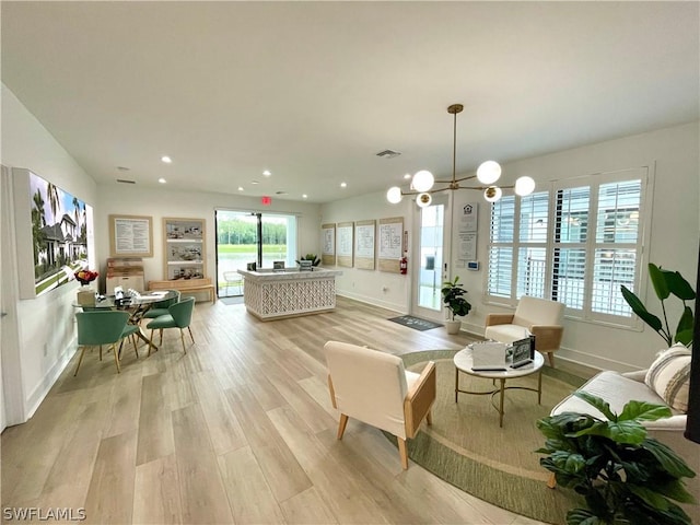 living room featuring an inviting chandelier, a healthy amount of sunlight, and light wood-type flooring