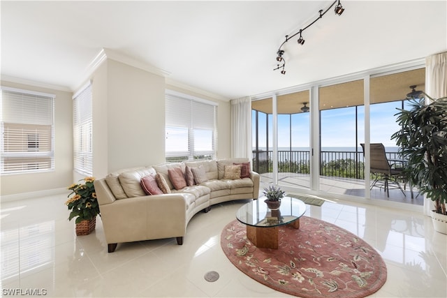 tiled living room featuring rail lighting, ornamental molding, expansive windows, and a water view