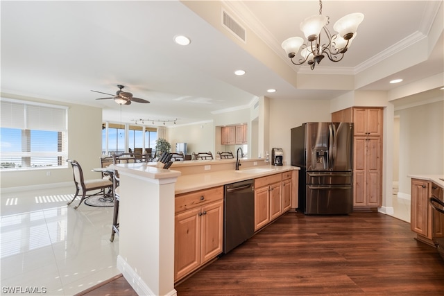 kitchen featuring ornamental molding, appliances with stainless steel finishes, a peninsula, a raised ceiling, and a sink