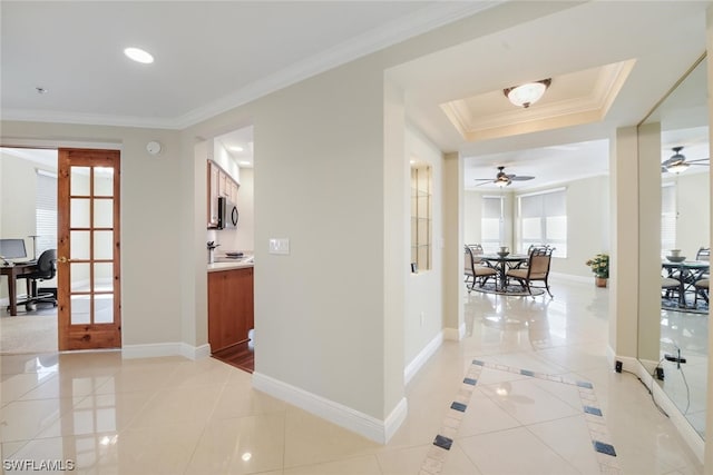 hall featuring a raised ceiling, french doors, crown molding, light tile patterned floors, and baseboards