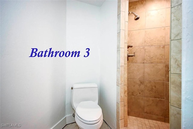 bathroom with a tile shower and toilet