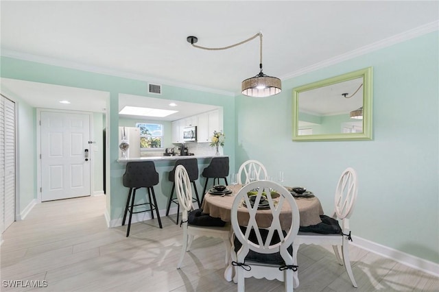 dining space with light hardwood / wood-style floors and ornamental molding