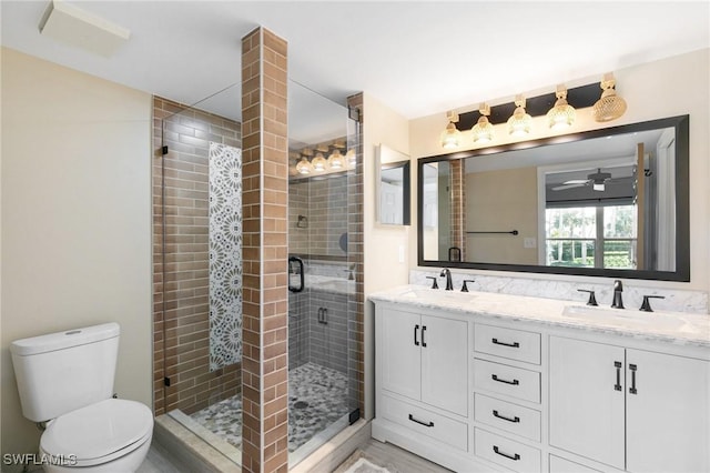 bathroom with hardwood / wood-style floors, vanity, ceiling fan, toilet, and a shower with shower door