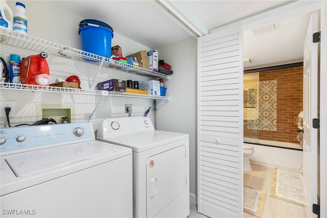 laundry area with washing machine and clothes dryer and hardwood / wood-style floors