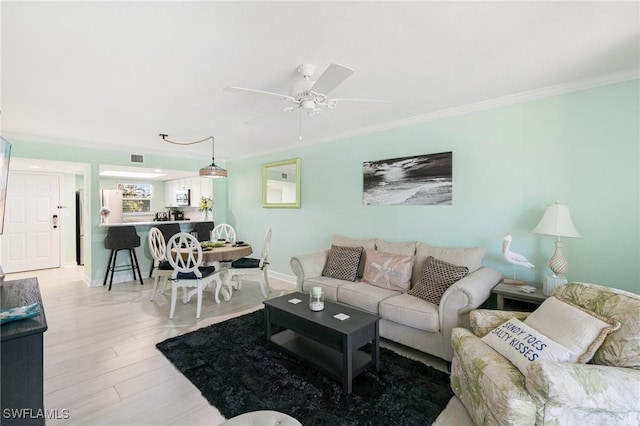 living room with light hardwood / wood-style floors, ceiling fan, and crown molding