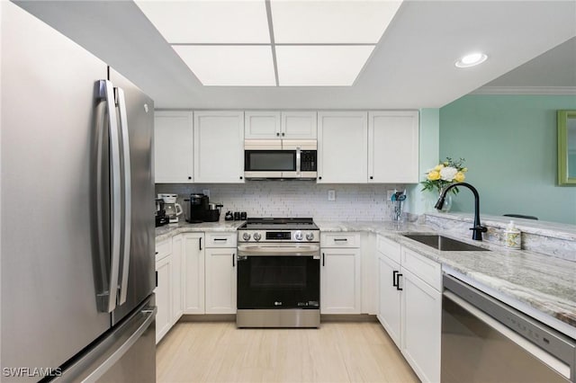 kitchen featuring light stone counters, sink, white cabinets, and stainless steel appliances