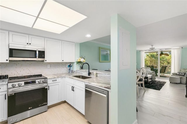 kitchen with appliances with stainless steel finishes, backsplash, white cabinetry, and sink