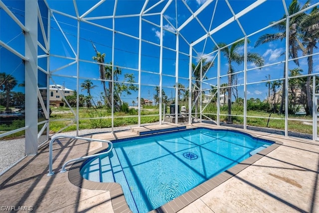 view of swimming pool featuring glass enclosure and a patio area