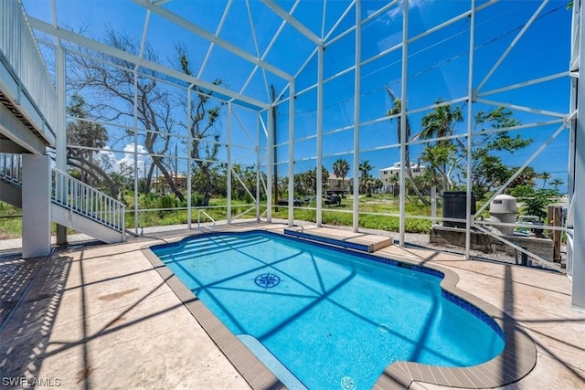 view of pool with glass enclosure and a patio area