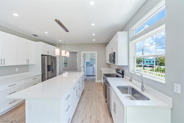 kitchen featuring stainless steel appliances, pendant lighting, sink, white cabinets, and a center island