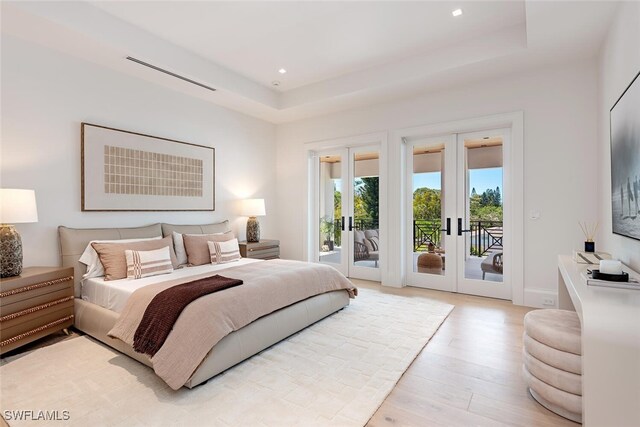 bedroom featuring light wood-style flooring, access to outside, recessed lighting, french doors, and a raised ceiling