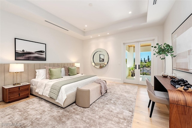 bedroom with visible vents, access to outside, a tray ceiling, french doors, and light wood finished floors
