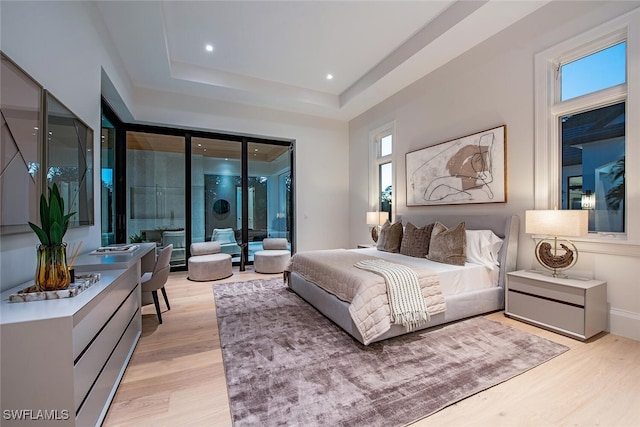 bedroom with baseboards, recessed lighting, a raised ceiling, access to outside, and light wood-type flooring