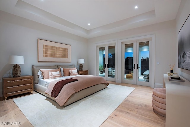 bedroom with a tray ceiling, french doors, and access to outside