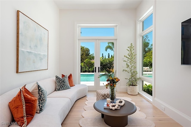 living area featuring french doors, plenty of natural light, baseboards, and light wood-style flooring