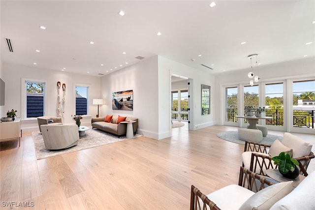 living area with a wealth of natural light, recessed lighting, light wood-type flooring, and baseboards