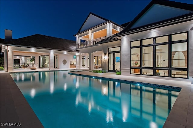 pool at night with an outdoor pool and a patio area
