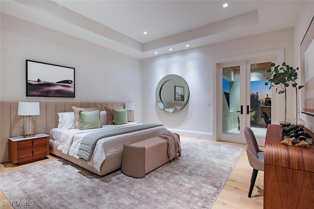 bedroom featuring recessed lighting, light wood-style flooring, a tray ceiling, and baseboards