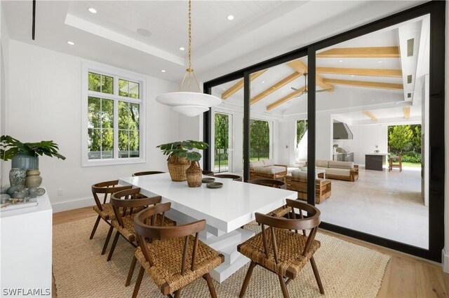 dining room with vaulted ceiling with beams, light hardwood / wood-style floors, and a wealth of natural light